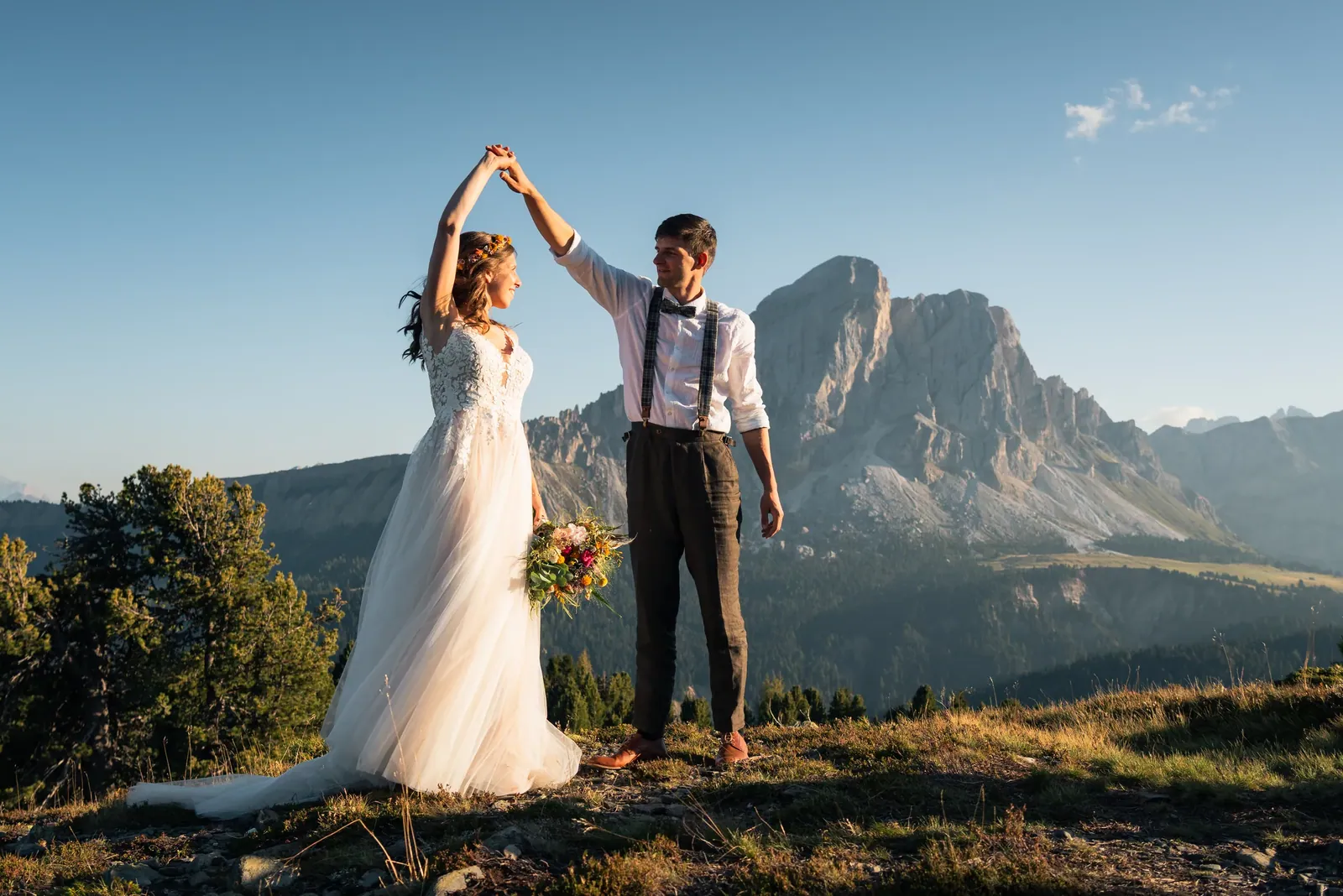 Brautpaar tanzt auf der Almwiese vor dem Dolomitengipfel