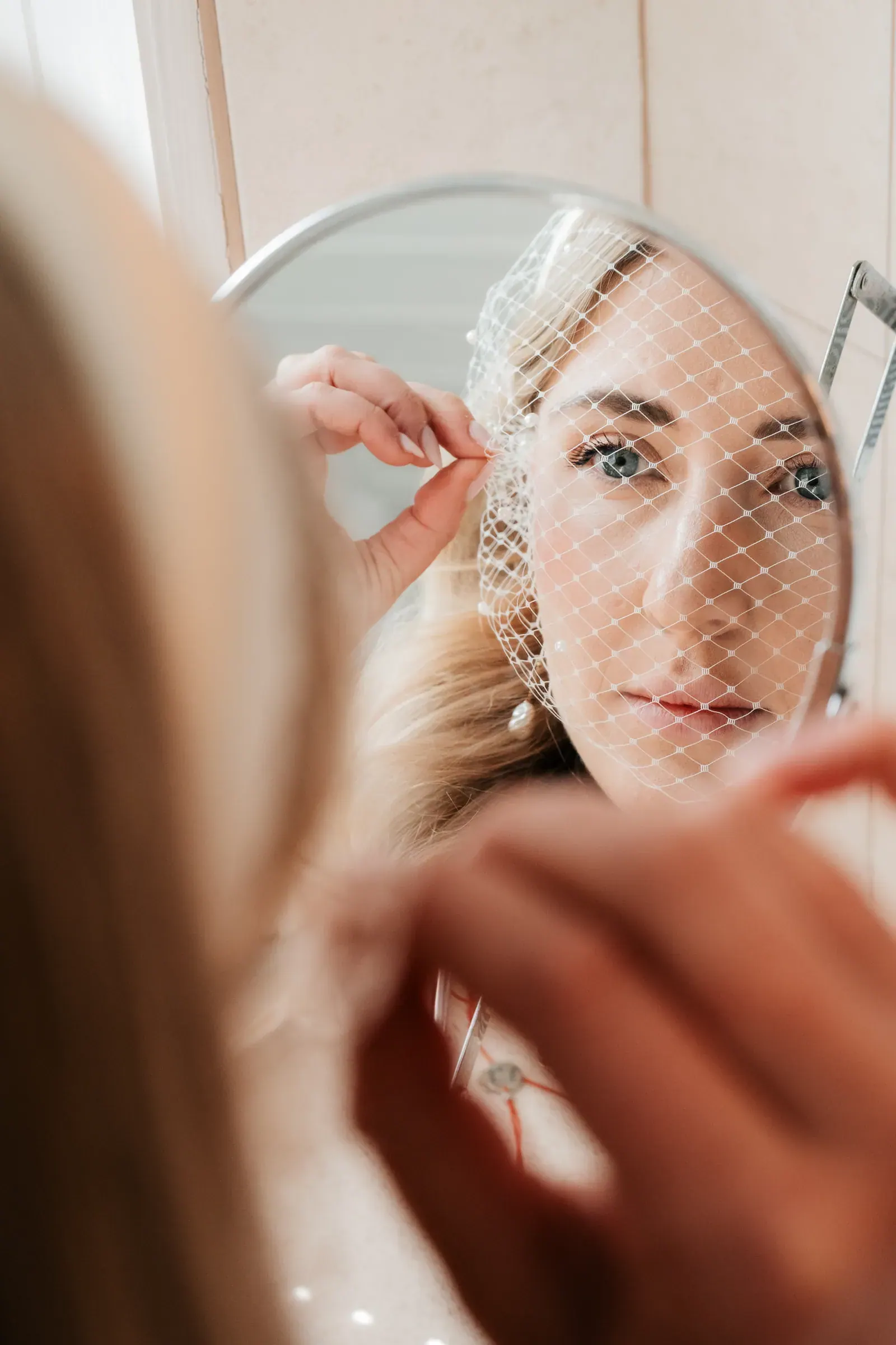 Braut richtet beim Getting Ready ihren Schleier vor dem Spiegel