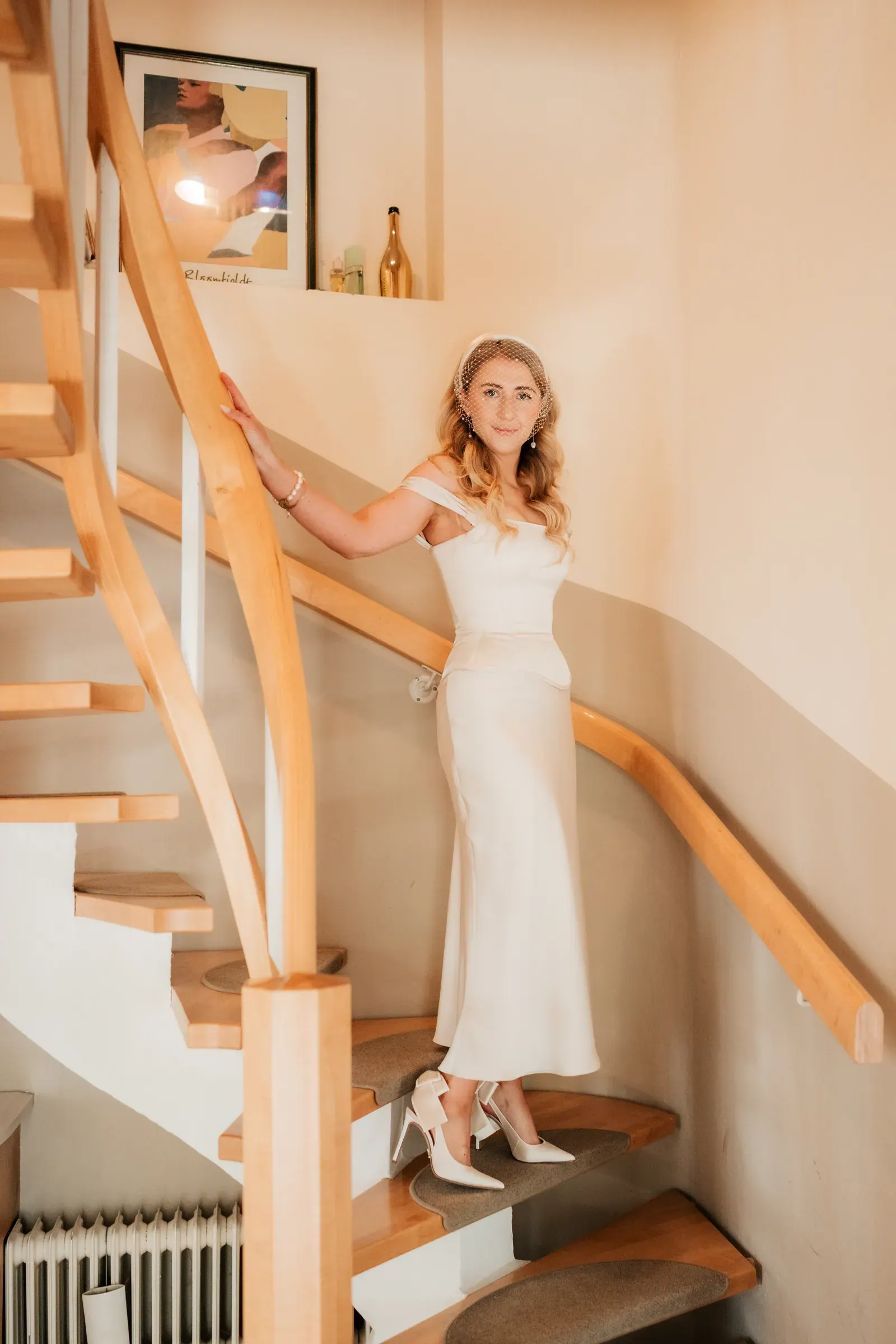 Braut im Brautkleid auf der Holztreppe im Elternhaus