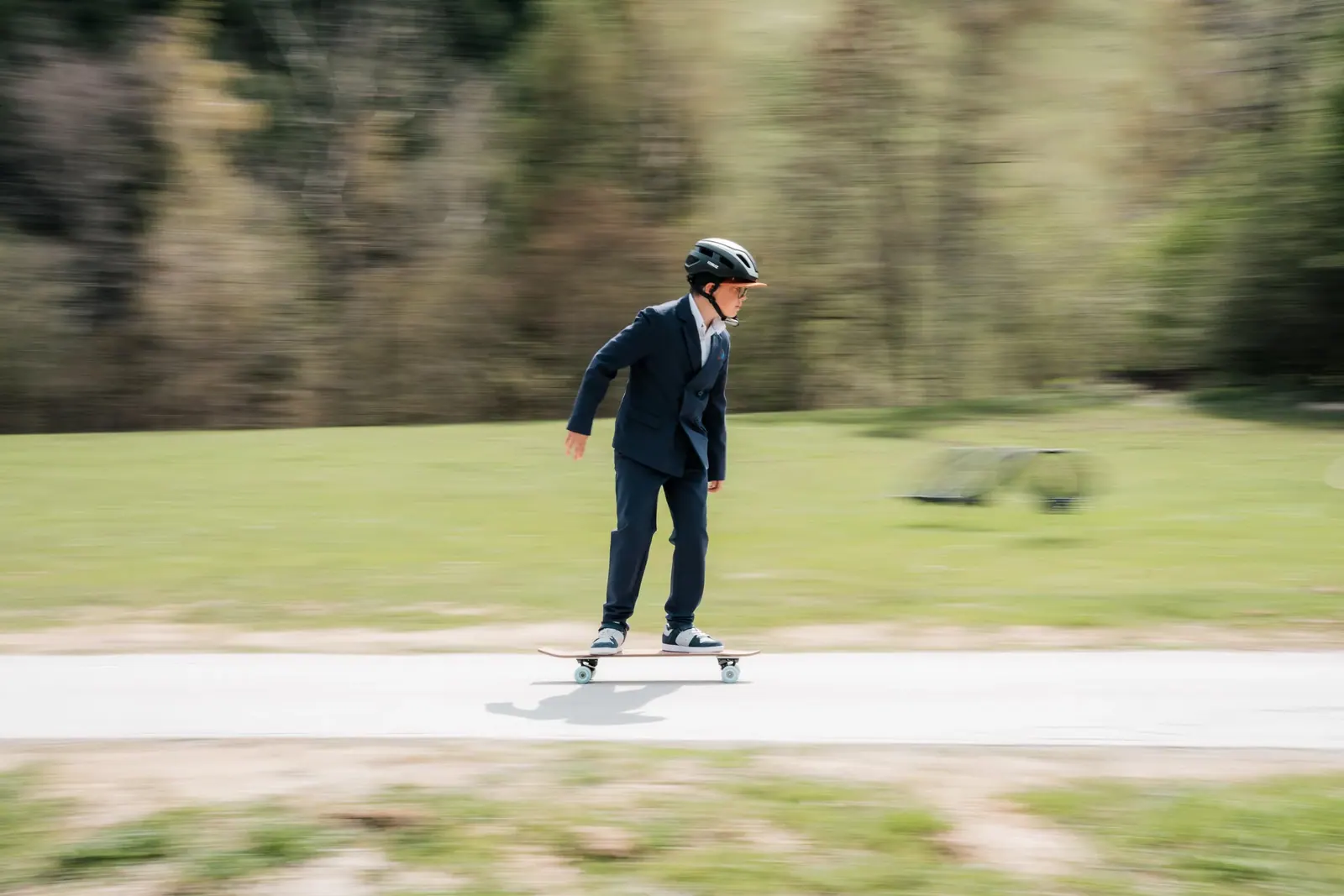 Junge im Anzug fährt bei der Feier vor der Flugschule Skateboard