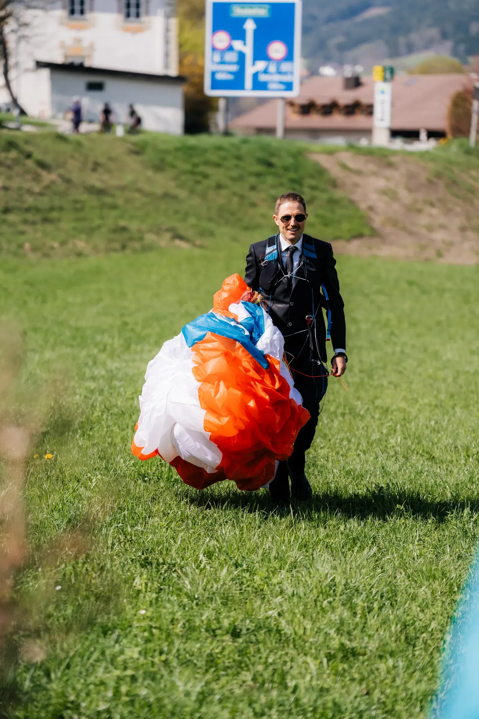 Bräutigam im Anzug packt nach der Landung seinen Gleitschirm zusammen